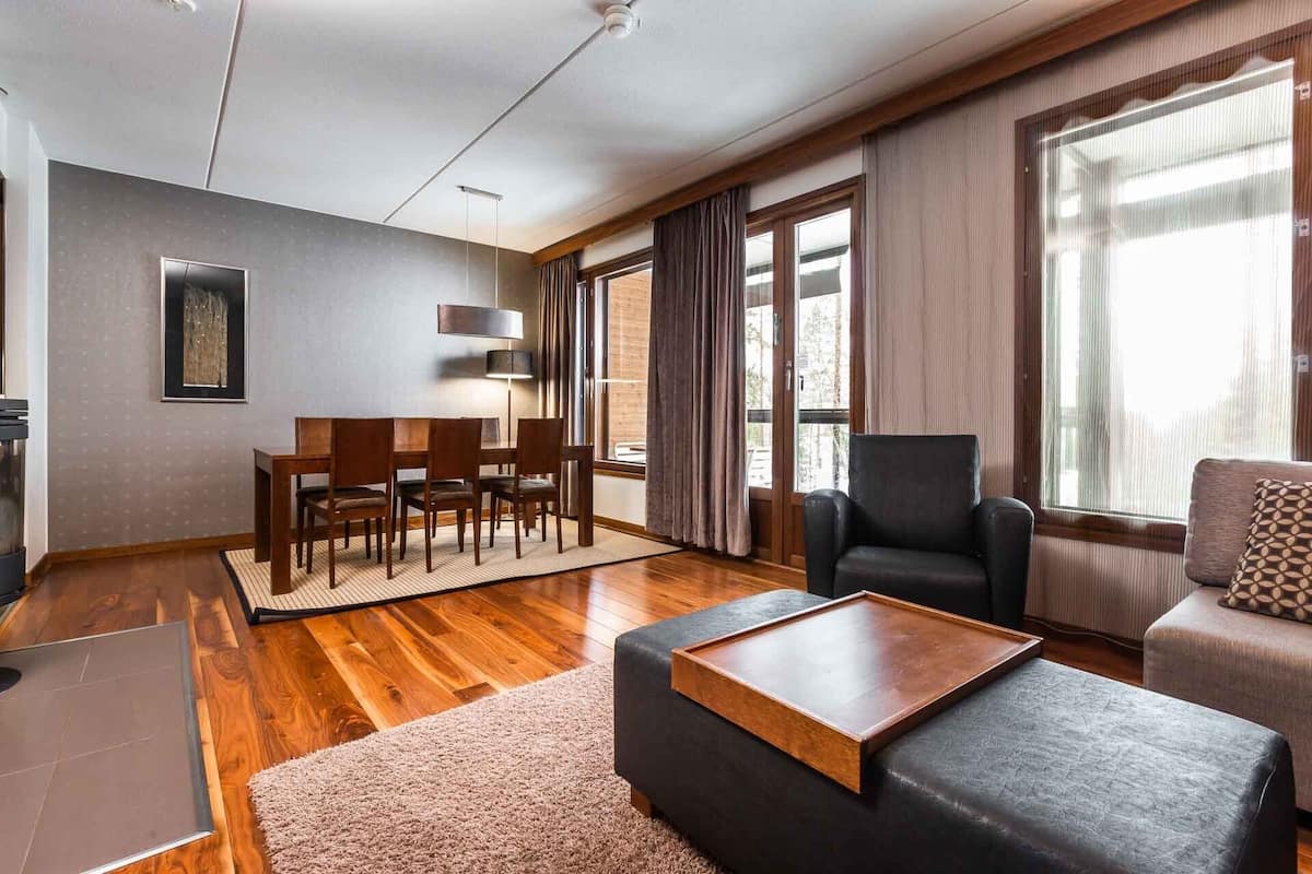 A modern living room with a dining area, large windows, and a fireplace.