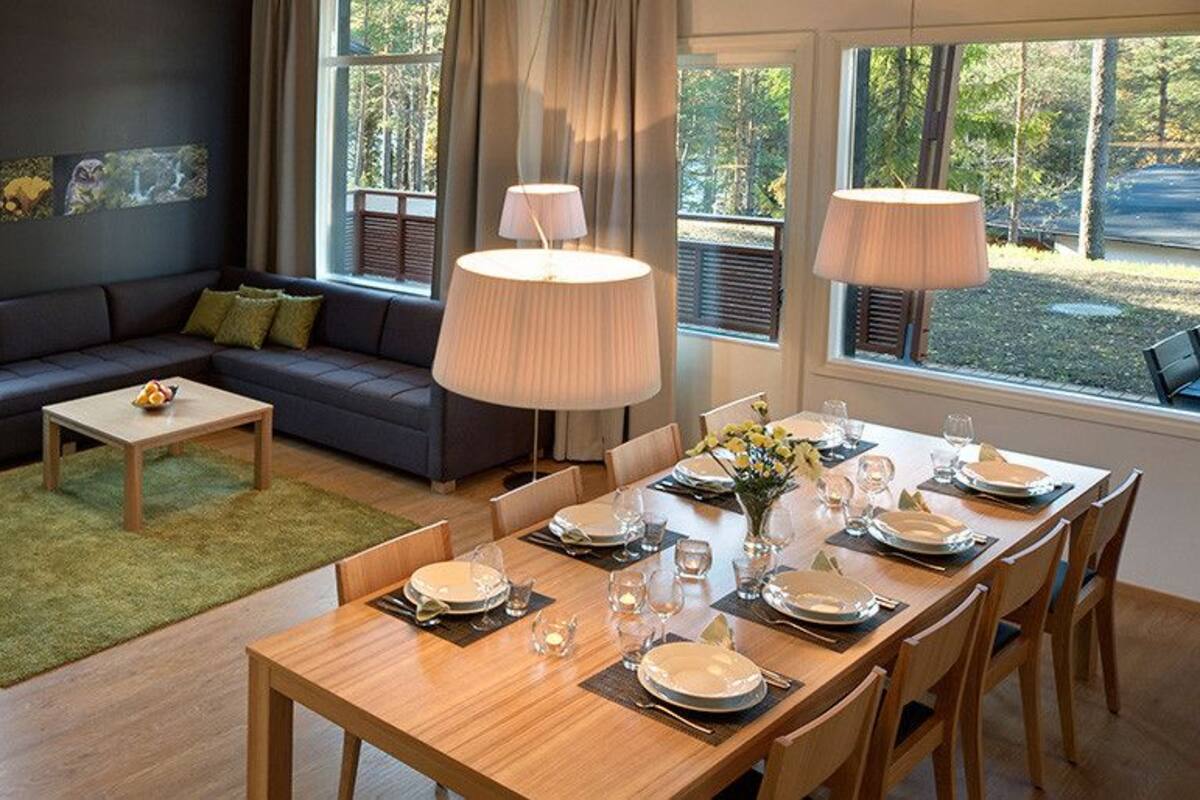 A modern living room with a sofa, coffee table, and dining table set for a meal.