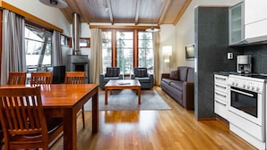 A modern kitchen with a built-in stove, a dining area with wooden furniture, and large windows offering a view of the outdoors. - Imatran Kylpylä Spa Apartments (Imatra)