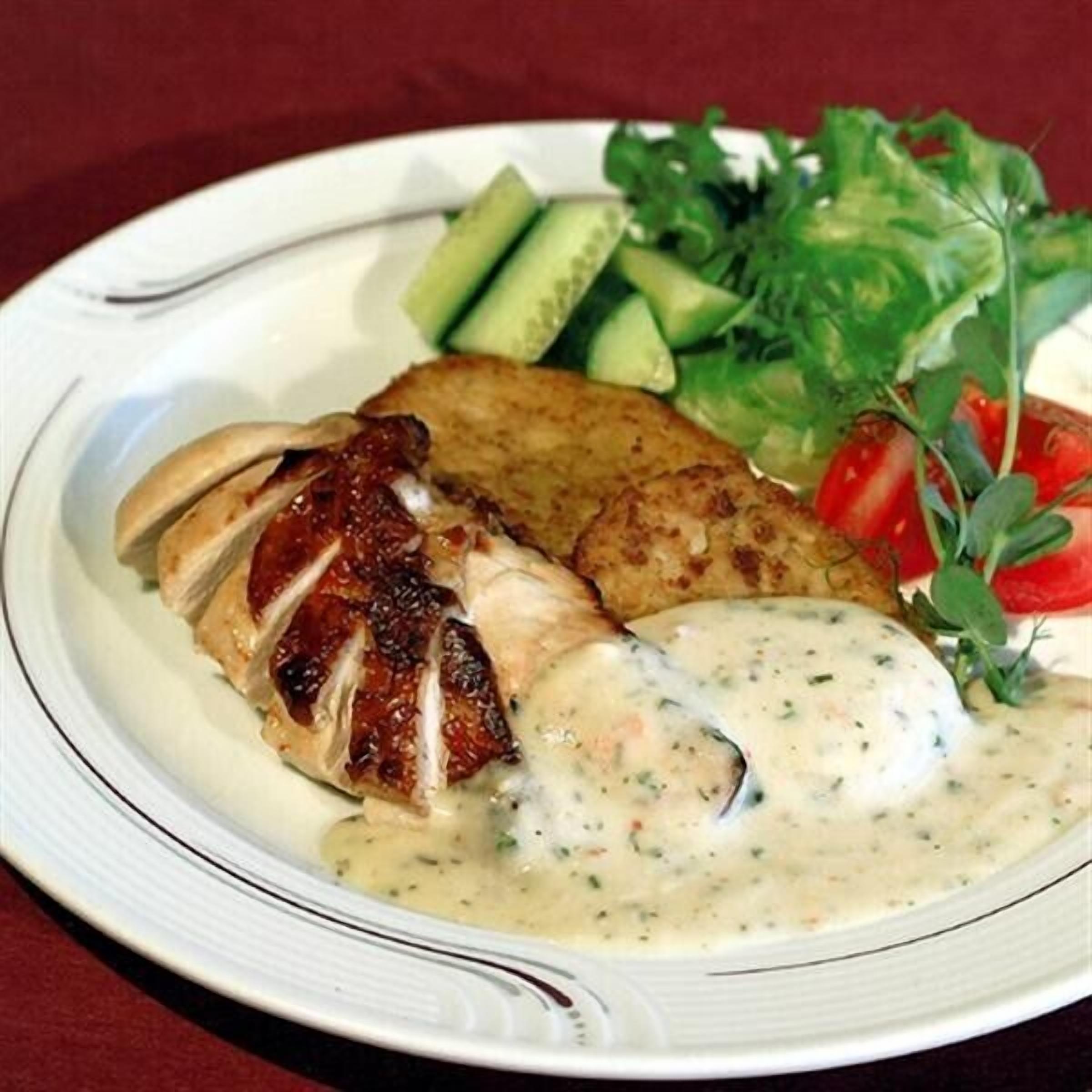 A plate with grilled chicken, a slice of potato, and a side salad.