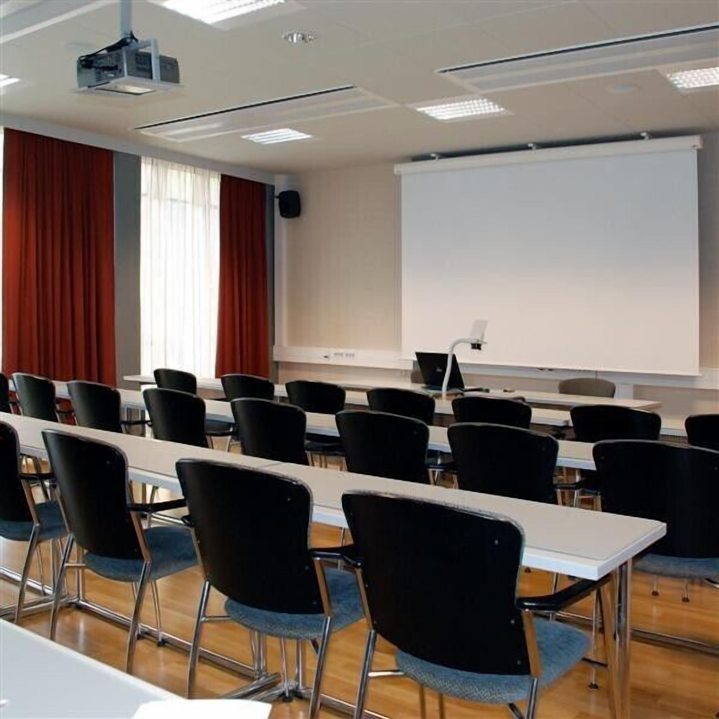A conference room with rows of chairs, a projector, and a whiteboard.