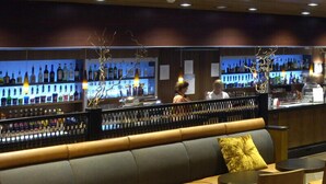 A bar area with a seating section, including a sofa and chairs, and a counter with bottles. - Imatra Spa Sport Camp - Hostel (Imatra)