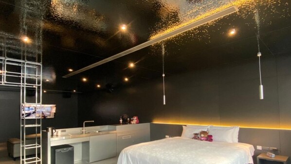 Una habitación de hotel moderna con una cama grande, un escritorio integrado y un espejo amplio.
