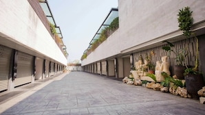 Ein modernes Gebäude mit einem zentralen Innenhof, das Beton und Glas kombiniert und einige Grünflächen aufweist.