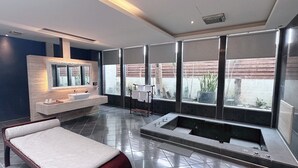Ein modernes Badezimmer mit einer großen Badewanne, einem separaten Waschbeckenbereich und einer Sitzecke mit einer Bank.