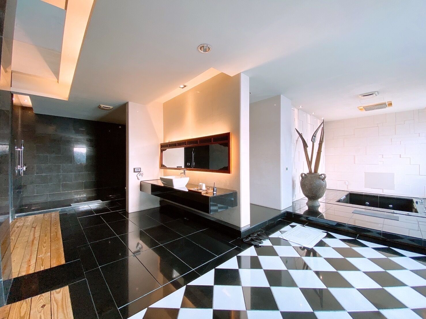 Um banheiro moderno com piso quadriculado em preto e branco, um espelho grande e um lavatório de madeira.