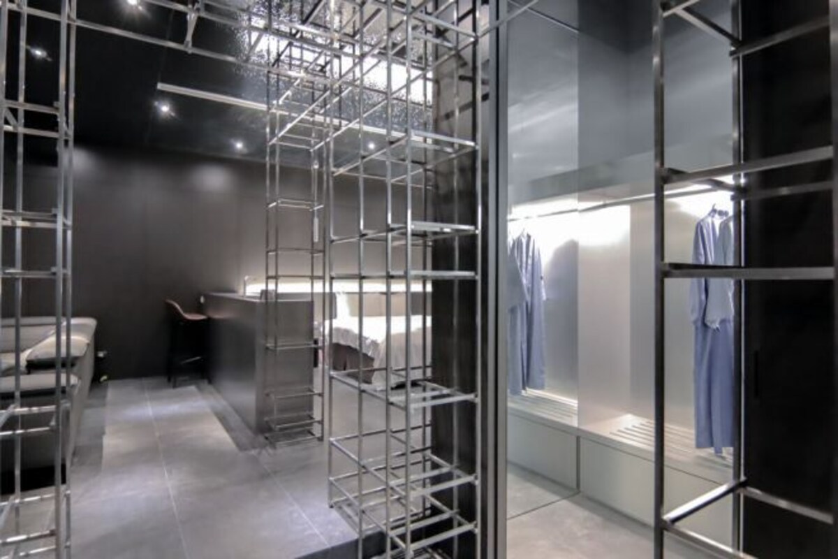 Una habitación moderna y luminosa con una estantería metálica, una zona de estar y un perchero.
