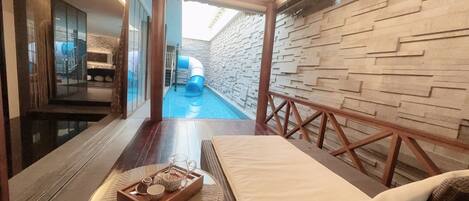 Un espace de bien-être moderne doté d’une piscine, d’un toboggan et d’une terrasse en bois.