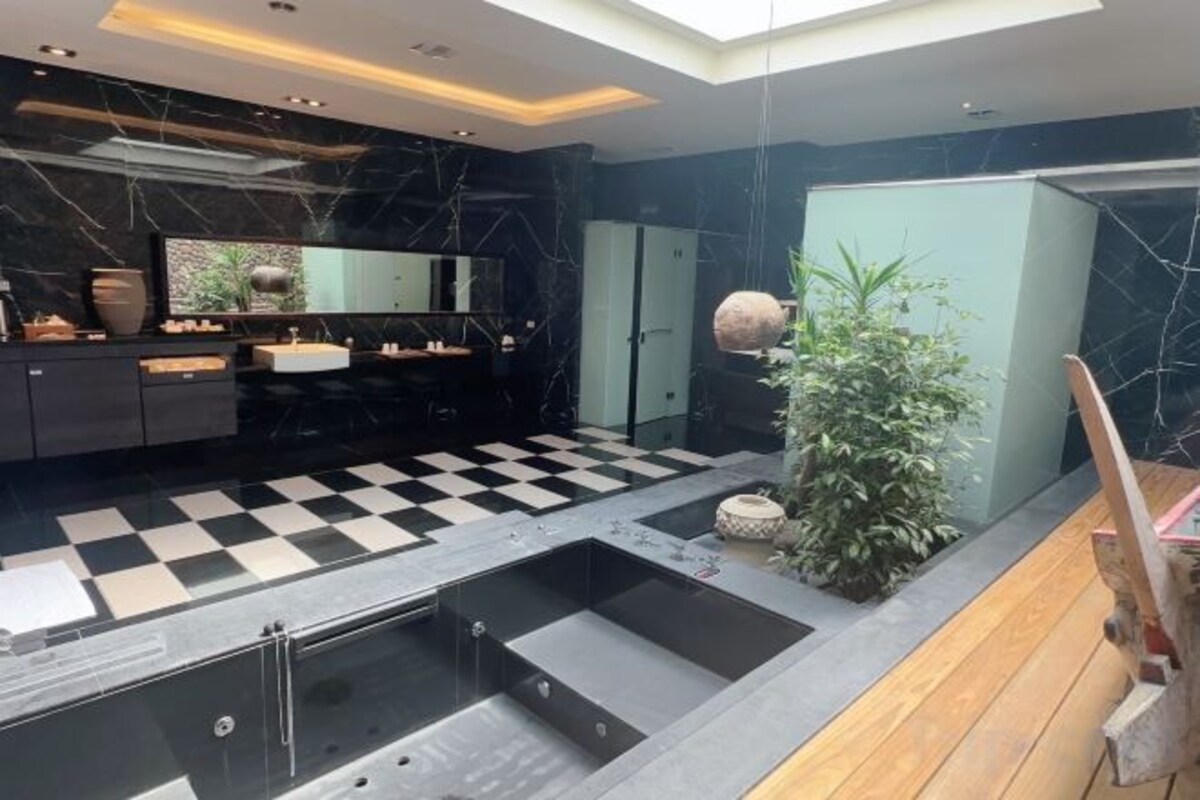 Un baño moderno con piso a cuadros, un espejo grande y una planta.