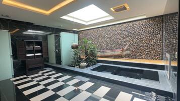 Eine moderne Lobby mit einem Schachbrettmuster-Boden, einer großen Felswand und einer Bootsausstellung.