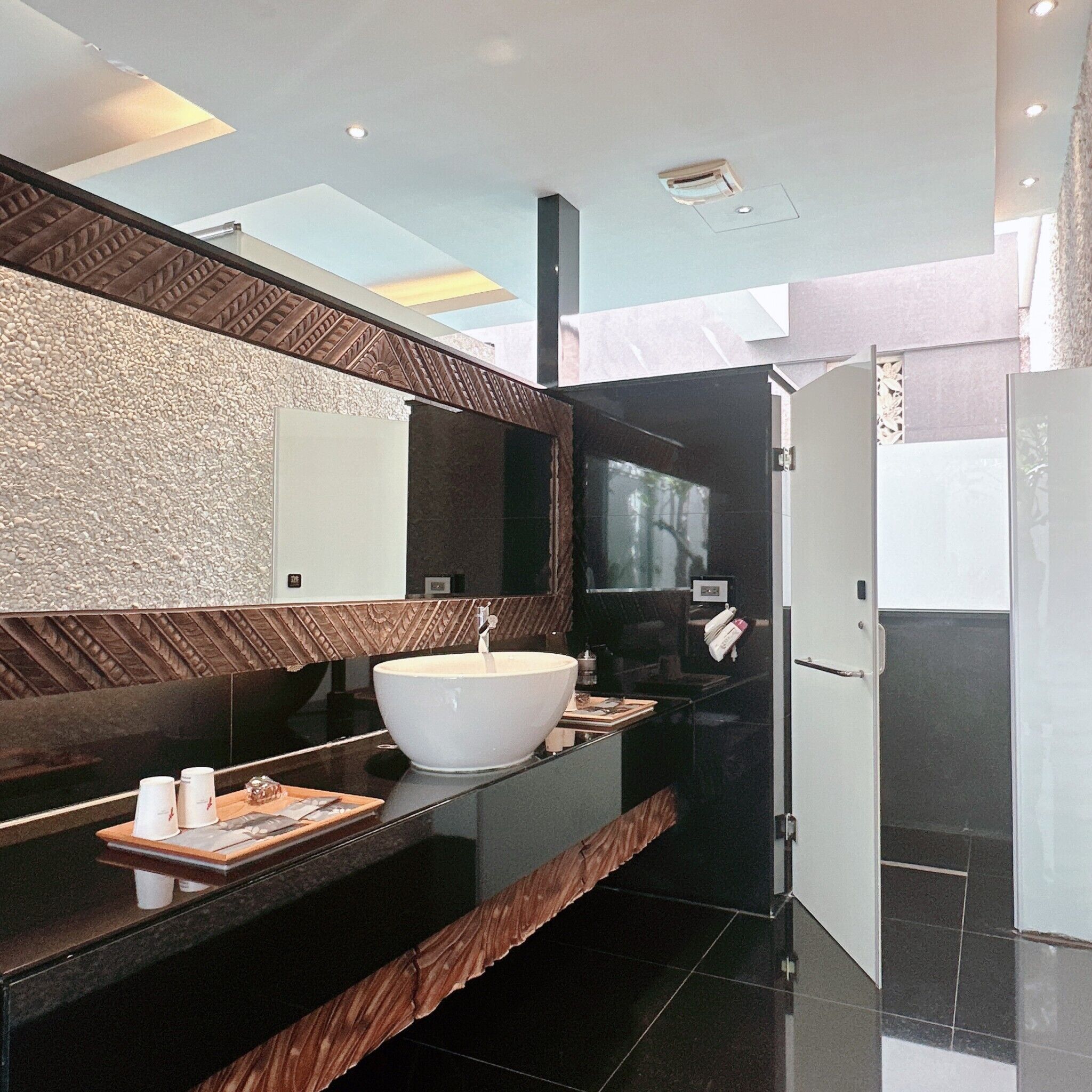 A modern bathroom with a large mirror, a white sink, and a black countertop.