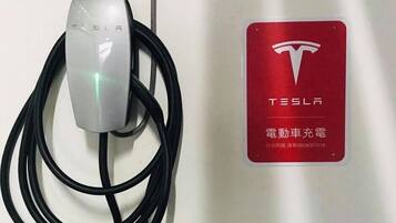 Una estación de carga Tesla con un letrero del logotipo Tesla en rojo.