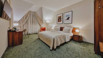 Een hotelkamer met een bed, een bureau, een stoel, een televisie en twee ingelijste foto's aan de muur.