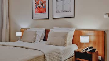 A hotel room with a bed, two bedside tables with lamps, and two framed posters on the wall.