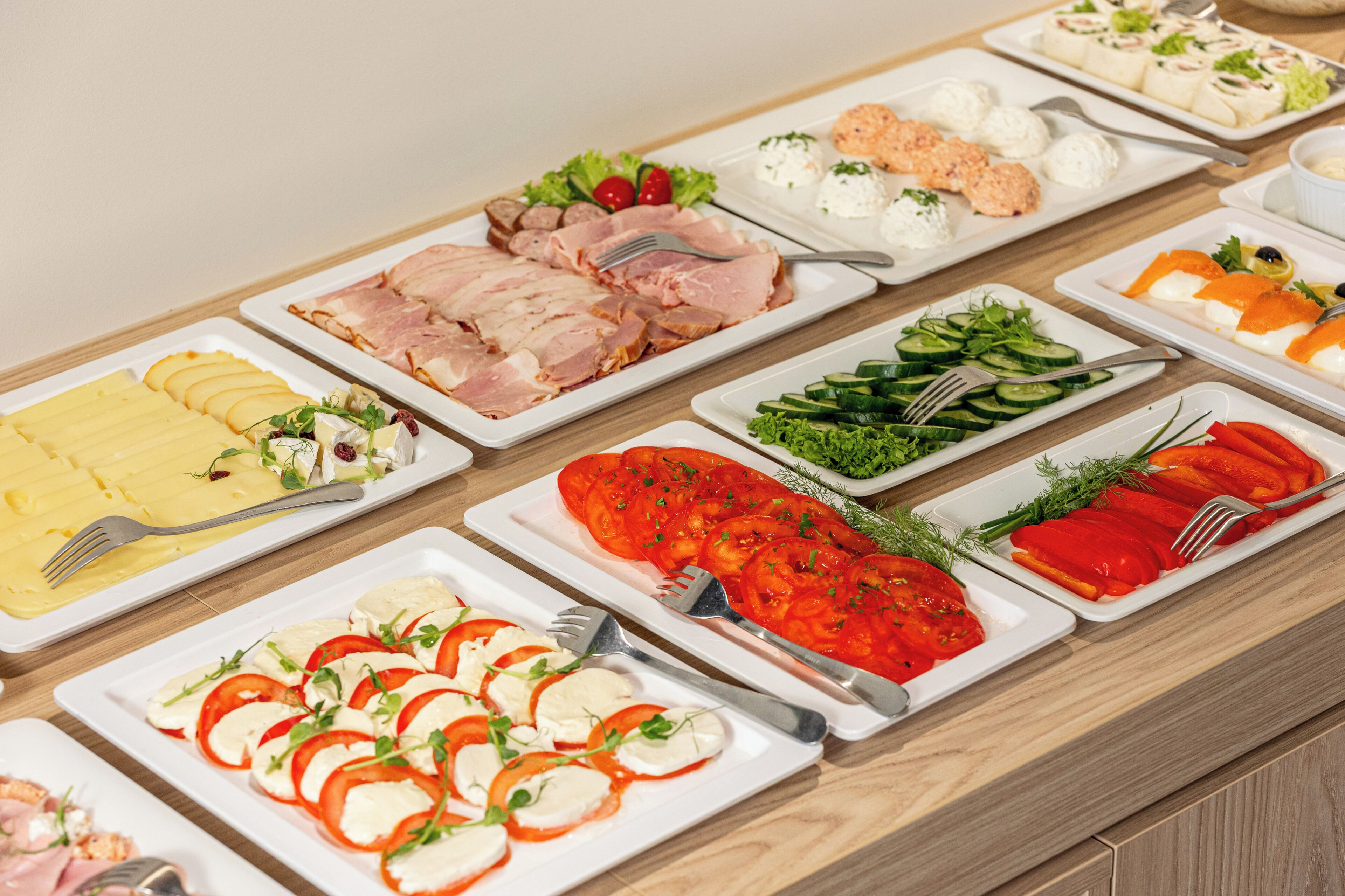 Un buffet proposant une variété d’aliments, notamment des viandes et des fromages en tranches, ainsi que des légumes.