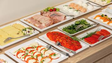 Un buffet proposant une variété d’aliments, notamment des viandes et des fromages en tranches, ainsi que des légumes.