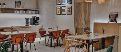 A modern cafe interior with wooden tables, orange chairs, and a coffee machine.