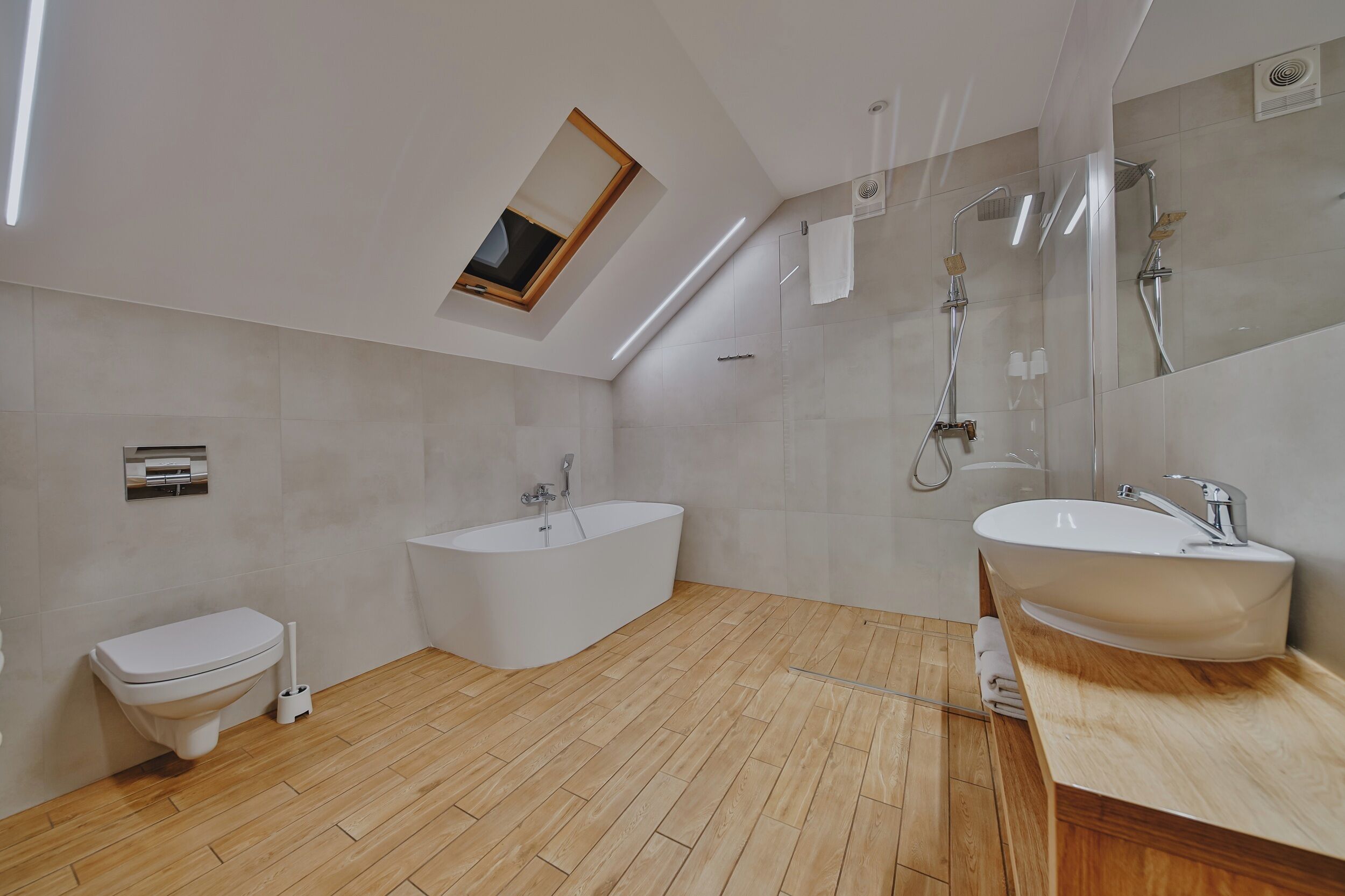 Ein modernes Badezimmer mit Dachfenster, freistehender Badewanne, Toilette und Waschtisch.