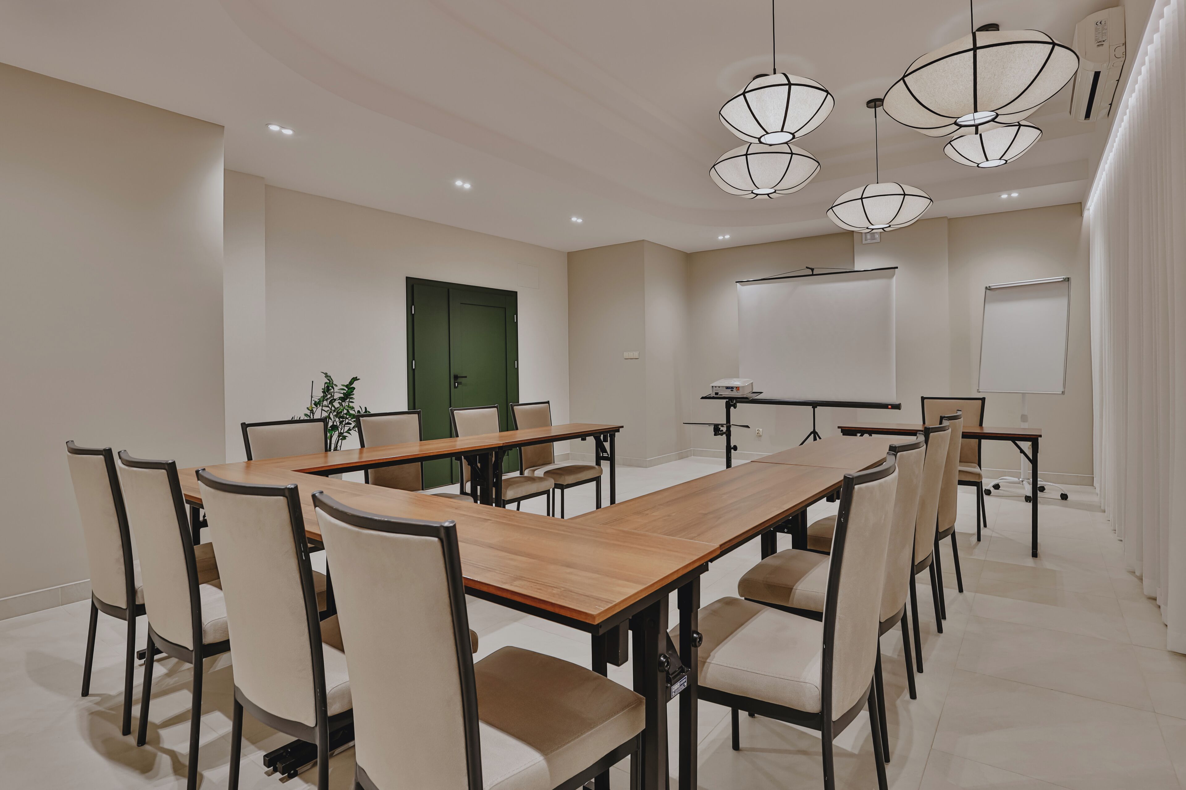 Une salle de conférence avec une longue table, des chaises et des luminaires au plafond.