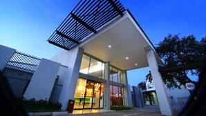 A modern building with a reception area, large windows, and a metal structure on the roof. - Travelodge Kasane (Kasane)