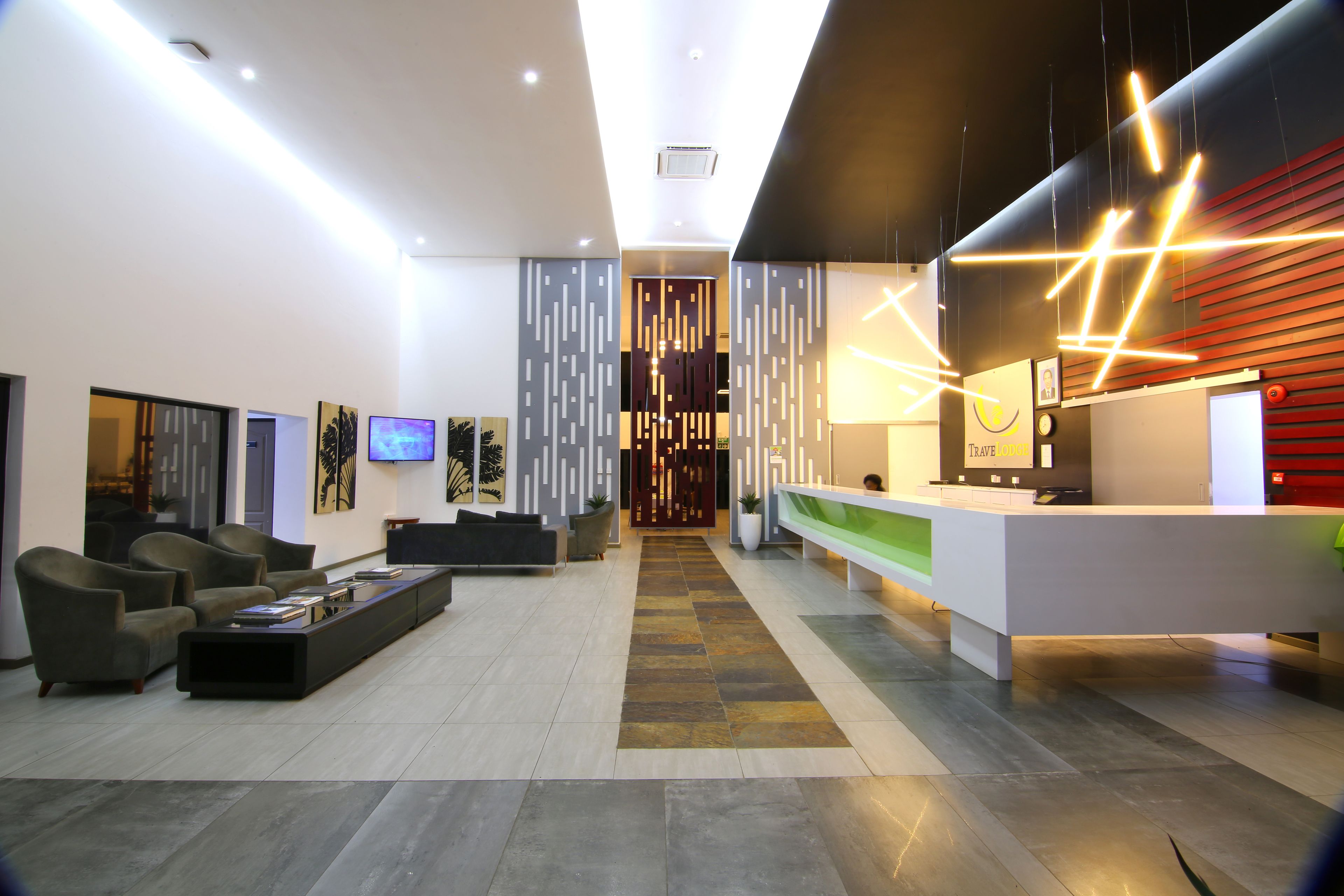 Un vestíbulo moderno con una recepción, zona de estar y una pared decorativa con motivos verticales.