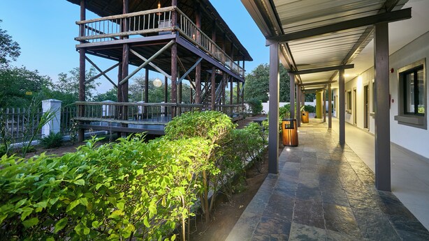 A wooden structure with a balcony, a covered walkway, and a building with windows. - Travelodge Kasane (Kasane)