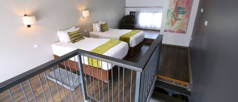 Habitación de hotel con dos camas, una escalera y un cuadro abstracto grande en la pared.