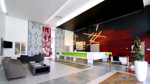 A modern reception area with a white desk, grey and red decor, and a Christmas tree. - Travelodge Kasane (Kasane)