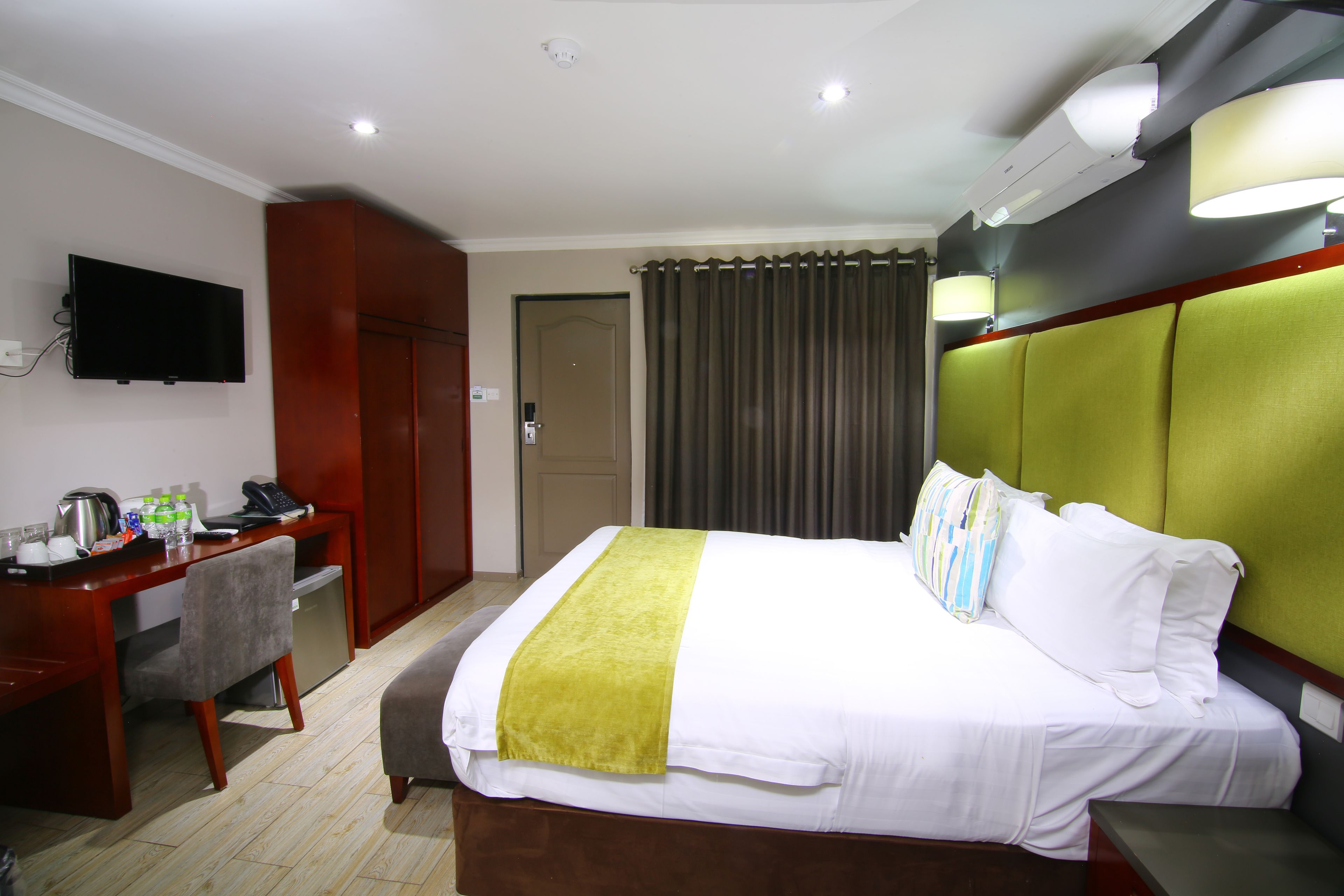 Una habitación de hotel con una cama, un escritorio con silla, un televisor y una puerta.