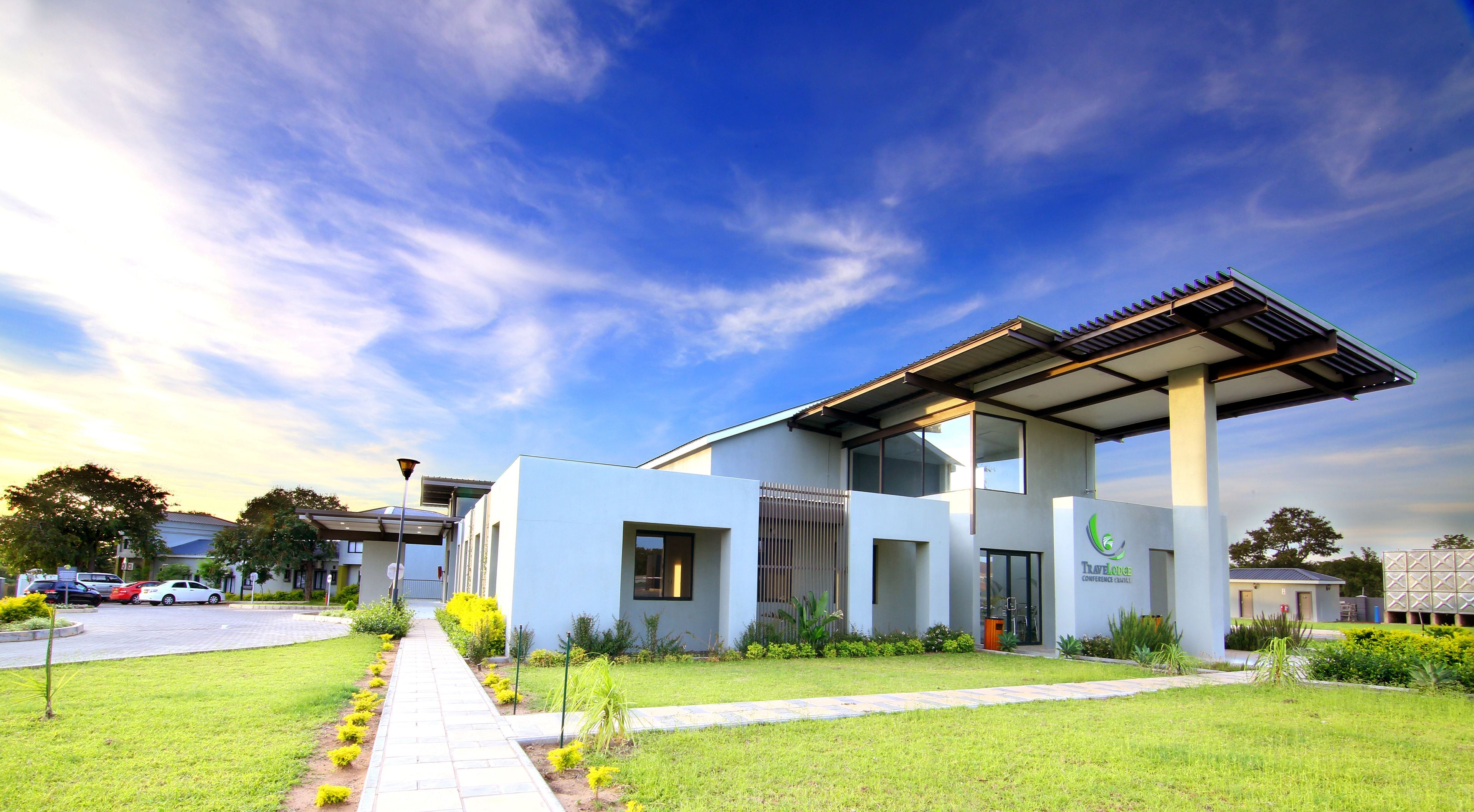 A modern building with a flat roof, large windows, and a pathway leading to the entrance.