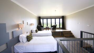 A hotel room with two beds, a small table, and a balcony with a view.