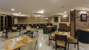 Restaurante com várias áreas de estar, incluindo cabines e mesas, e uma parede de destaque em tijolo.