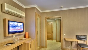 Quarto de hotel com televisão, escrivaninha, cadeira e cama.