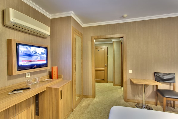 Una habitación de hotel con televisión, escritorio, silla y cama.