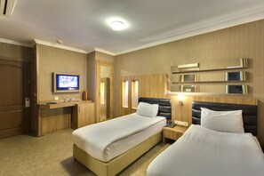Habitación de hotel con dos camas, televisión, escritorio y espejo.