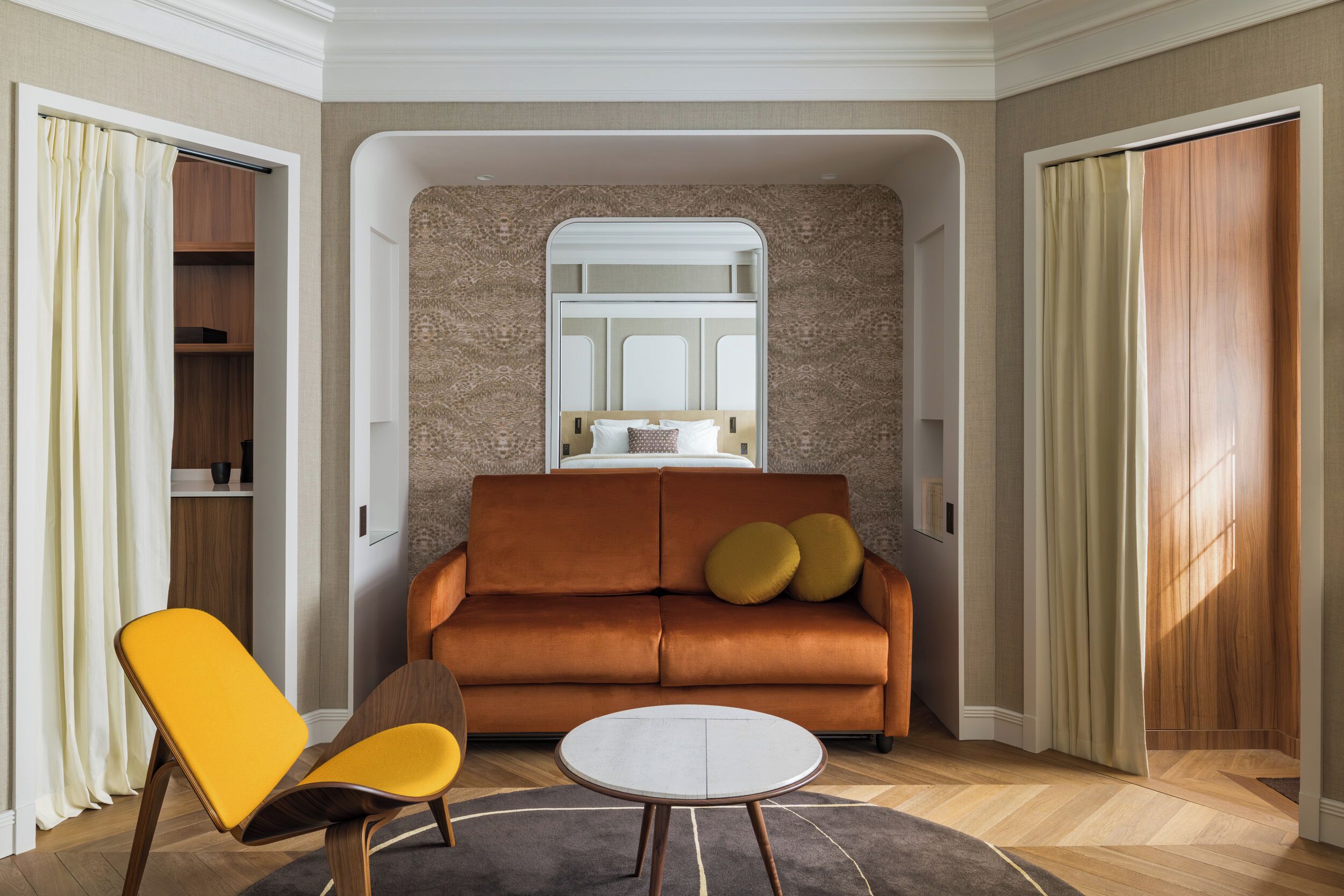 A modern living room with a sofa, two chairs, a small table, and a window.