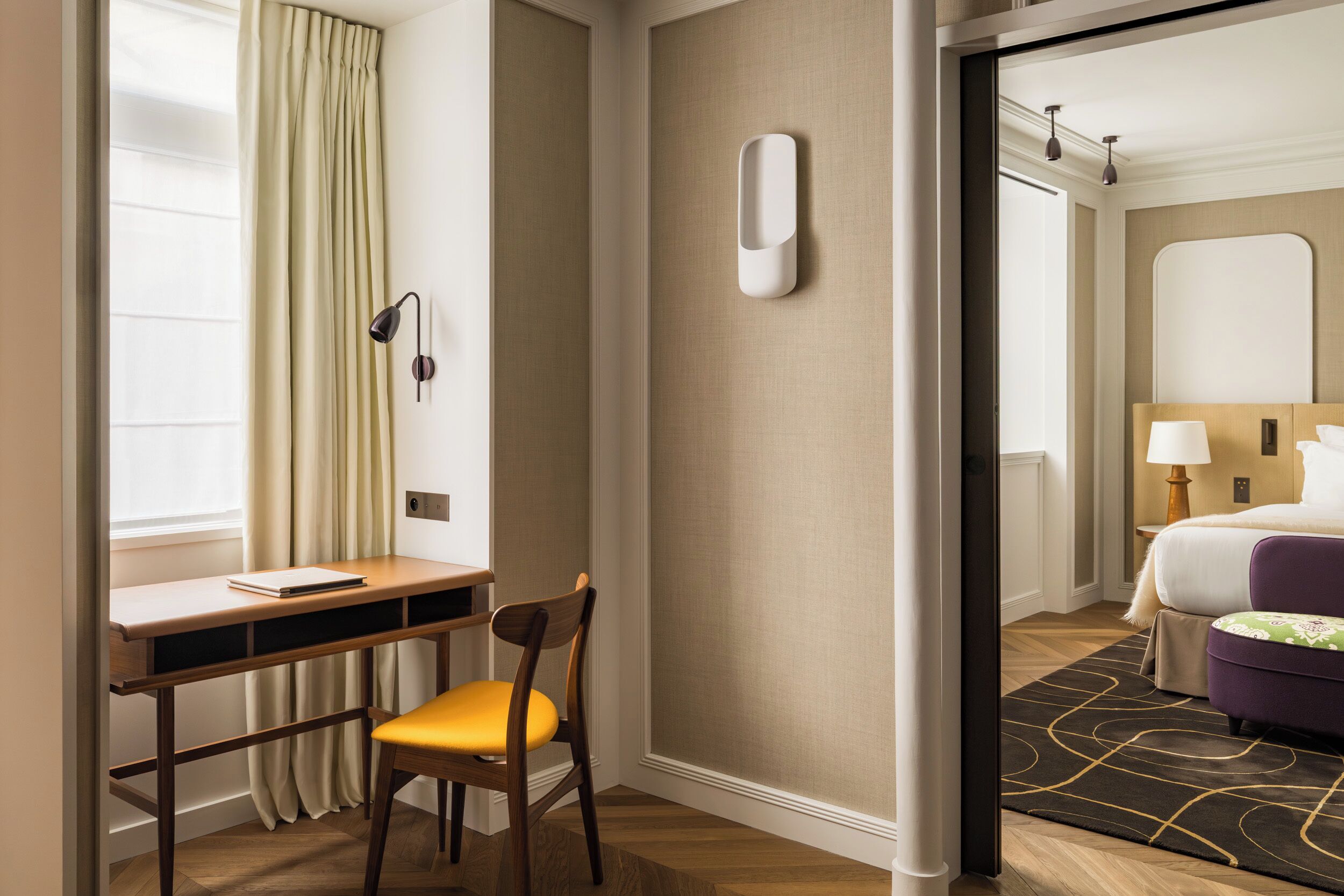Ein Hotelzimmer mit Schreibtisch, Stuhl und einem Bett mit violettem Kopfteil.