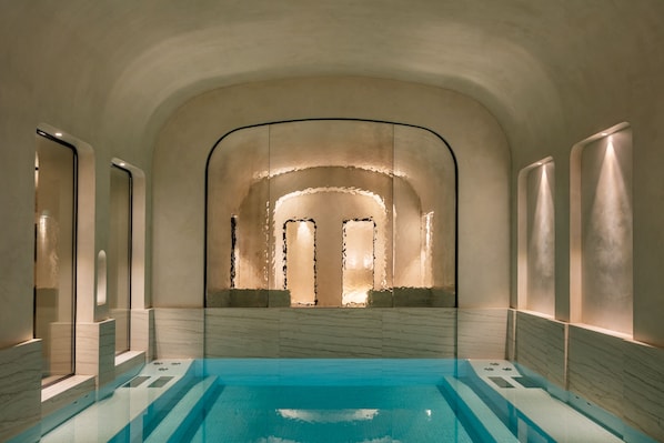 A spa area with a pool, arched ceiling, and marble walls.