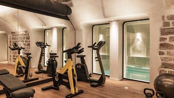 Un gimnasio con equipamiento de ejercicio, una banca y una pesa rusa.