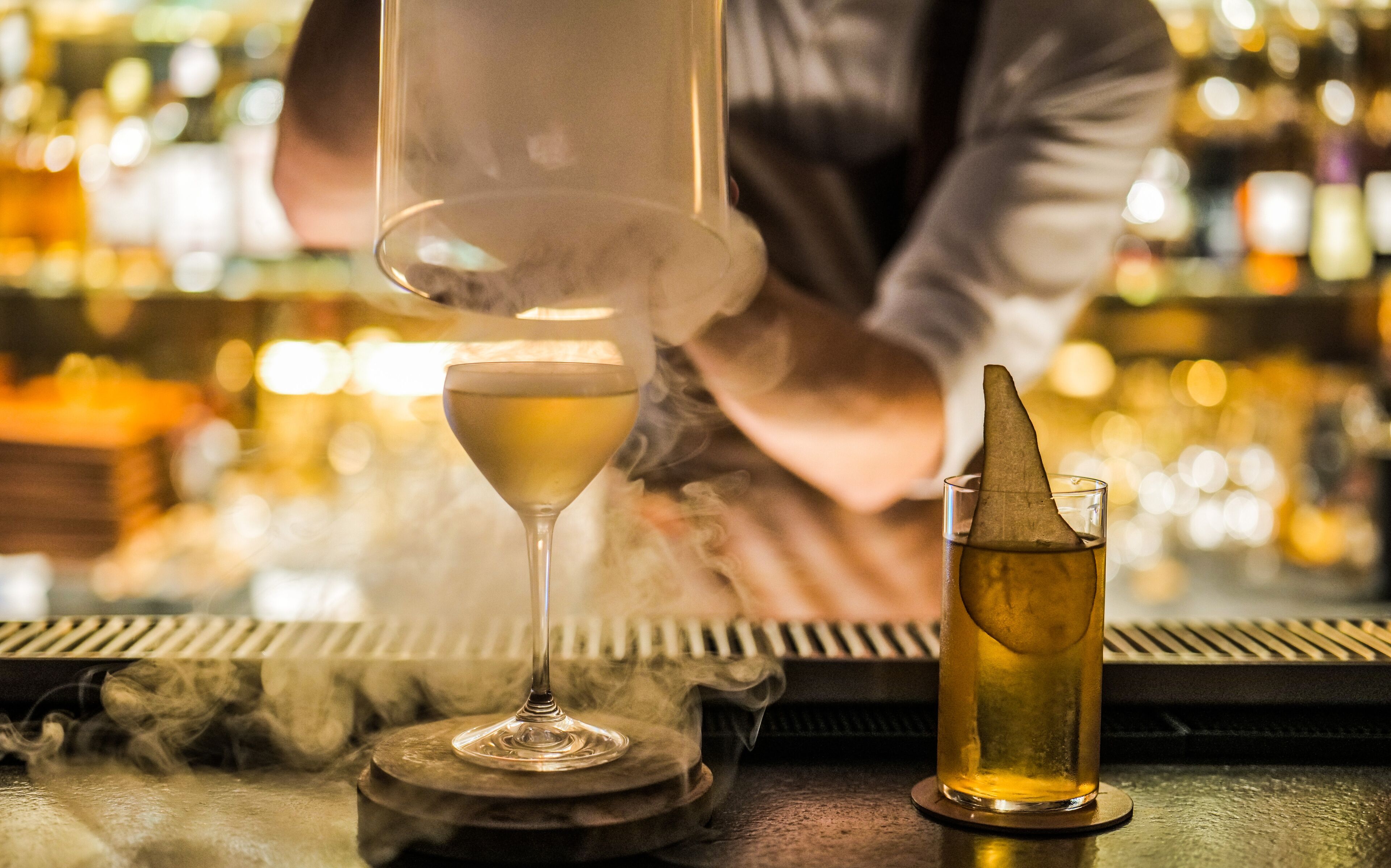 Een barsetting met een cocktailglas en een fles drank op een onderzetter.