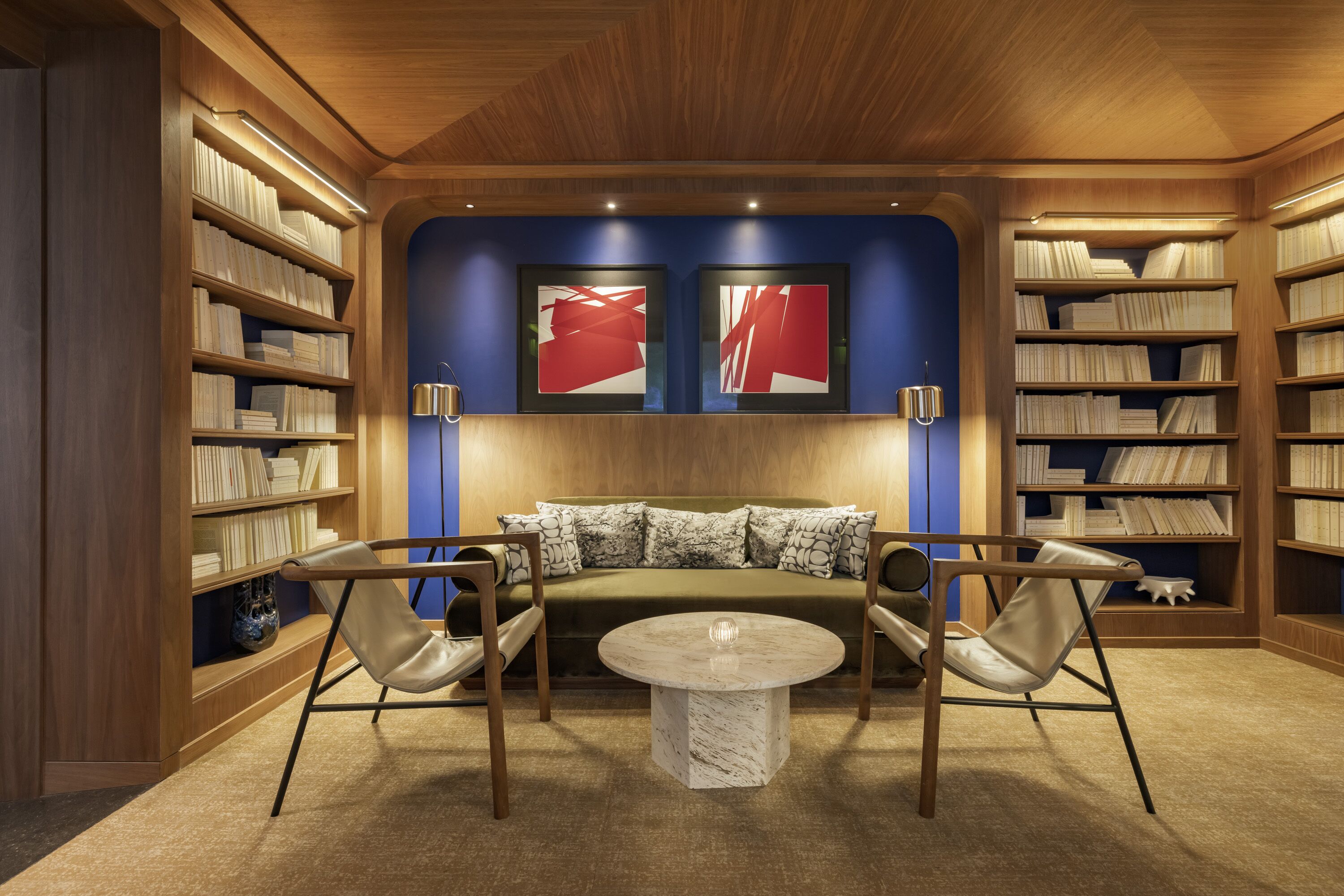 A library with bookshelves, a sofa, and two chairs.