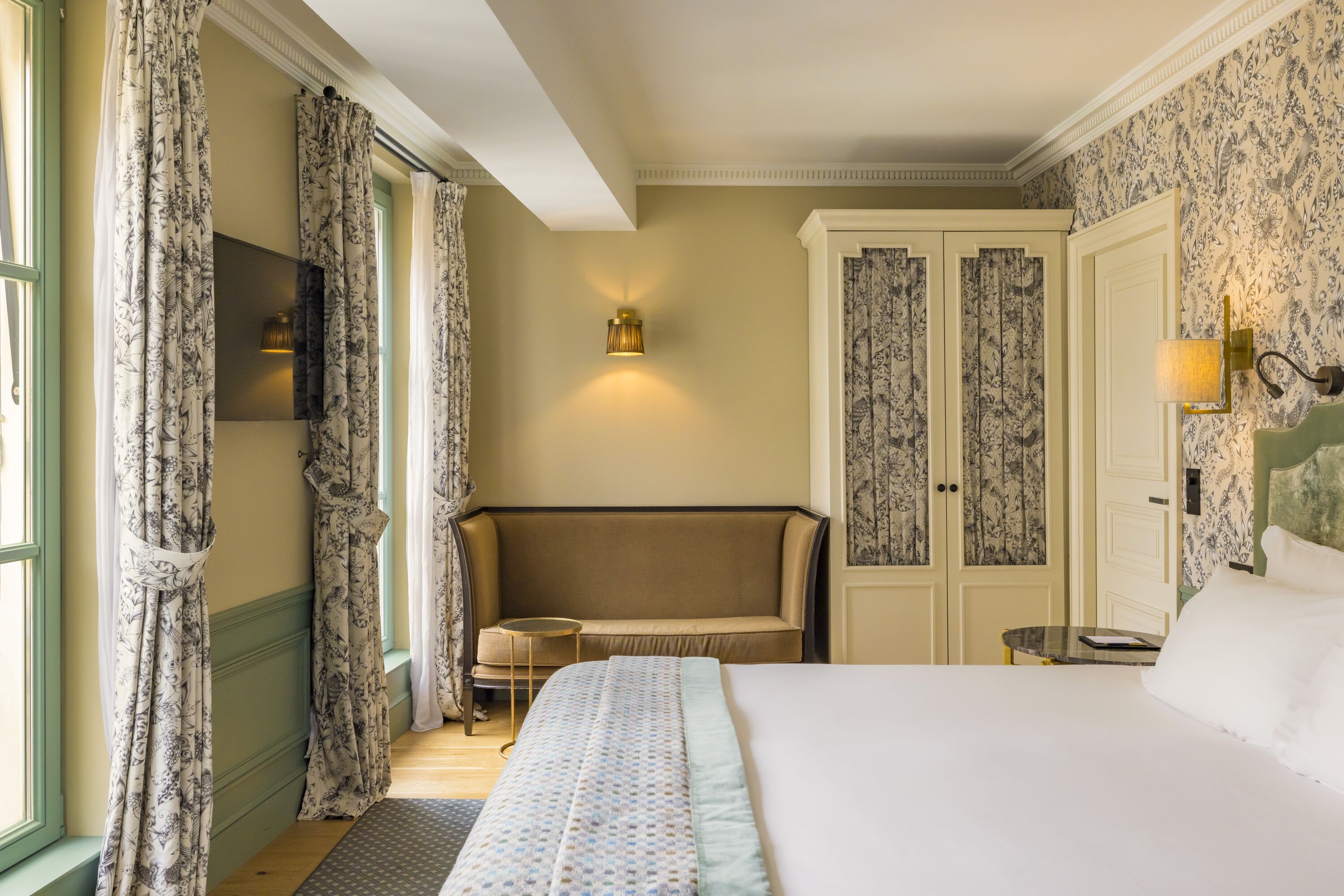 Ein Hotelzimmer mit einem Bett, einer Couch, einem Fernseher, einem Kleiderschrank und einer Wandlampe.