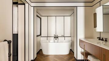 Ein modernes Badezimmer mit einer freistehenden Badewanne, einem Waschtisch mit Spiegel und einem Fischgrätenparkettboden.