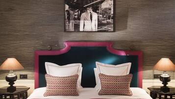 A hotel room with a large bed, two bedside tables with lamps, a headboard, and a framed picture on the wall.