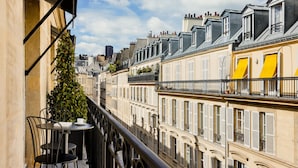A balcony with a table and chairs, overlooking a row of buildings with shutters and a clear sky. - Pavillon Faubourg Saint-Germain & Spa (Paris)
