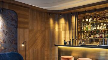 Zona de bar con pared de madera, sillas azules y una barra con taburetes.