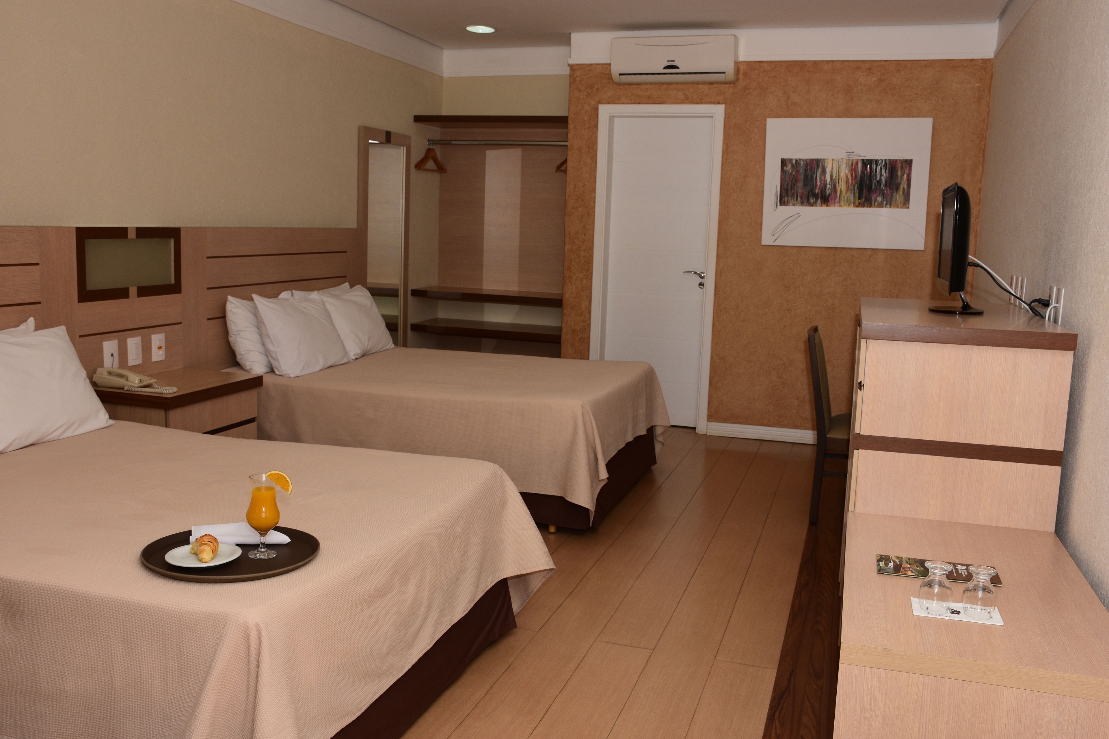 Een hotelkamer met twee bedden, een bureau, een stoel en een klein tafeltje met een ontbijtserver.