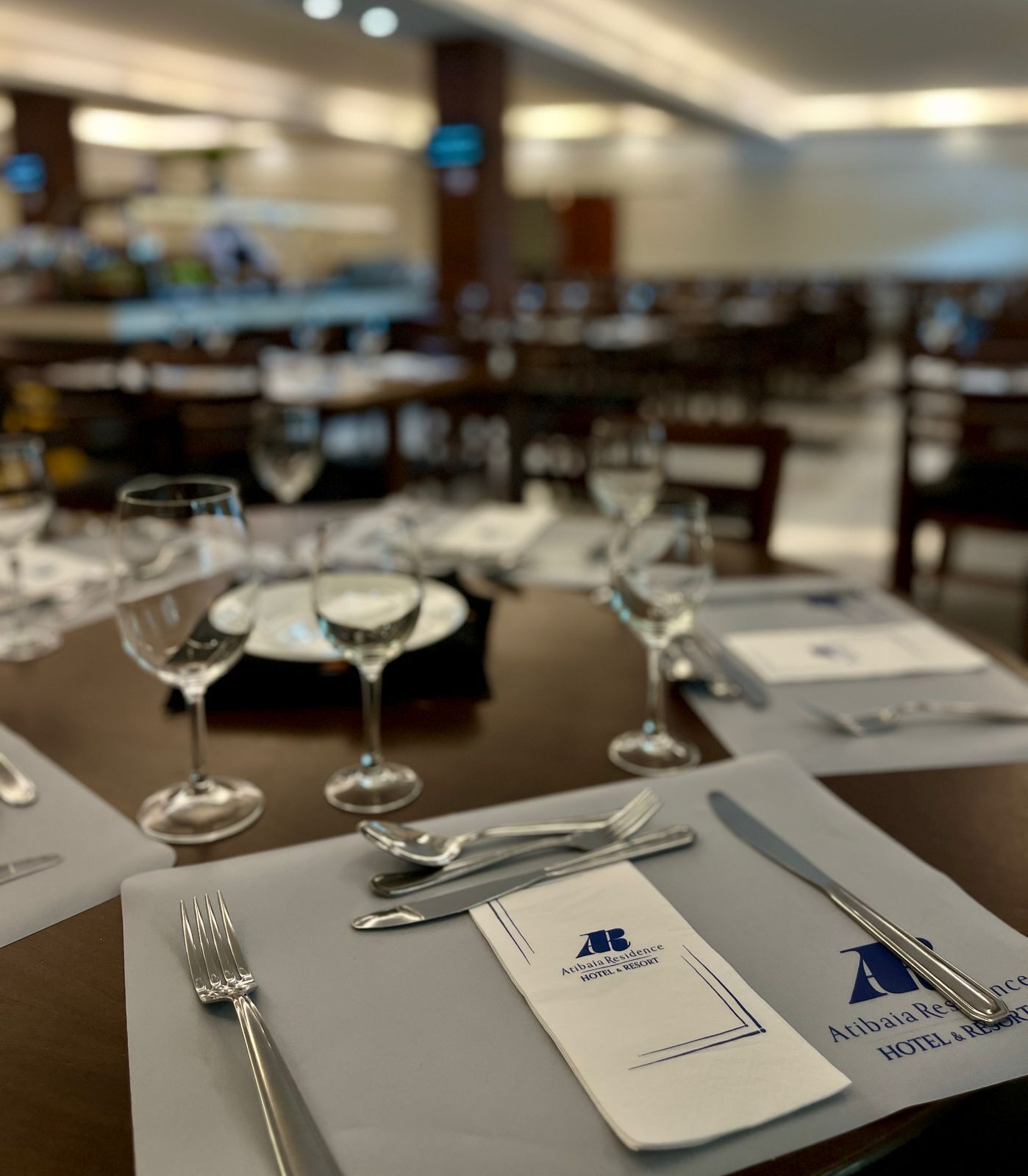 A dining table set with cutlery and wine glasses, with a menu on the table.