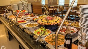 A buffet with various dishes, including salads, meats, and desserts, arranged on a counter with a glass barrier.