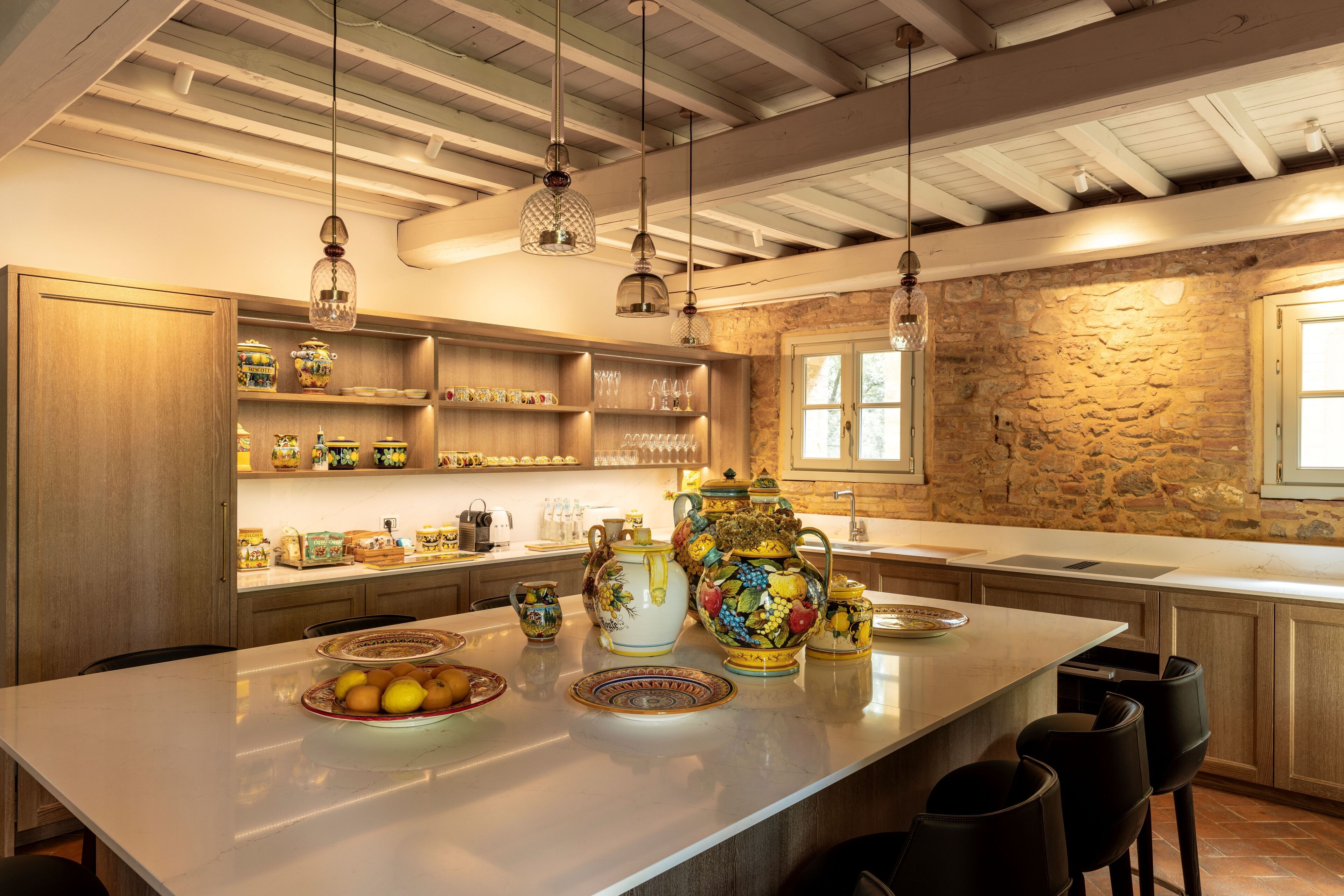 A kitchen with a large island, wooden cabinets, and a stone wall.
